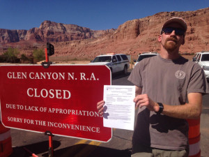 Boater Alan Cammack holds his permit in front of a "Closed" sign at the Glen Canyon National Recreation area. Photo by Scott Davis of Ceiba Adventures.
