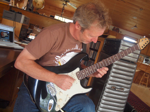 Bruce Hayes staked his claim to fame with his creation of the Stratobassto, modifying the neck of a baritone guitar to work on a Stratocaster body in order to play an octave lower. Here, he demonstrates the instrument inside his home studio in Howard. Photo by Ericka Kastner