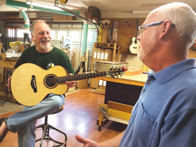 Luthier Jeff Bamburg, at right, visits at his Salida workshop with Massachusetts musician Bruce Mandel, who is holding a FSC model in Sapele and European Spruce. Musicians from around the U.S. can often be found visiting the shop to chat and try out a Bamburg guitar. Photo by Mike Rosso.