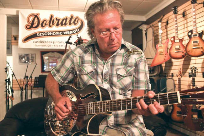 Kent Viles, inventor of the “Dobrato,” strums the strings of his invention in his Gunnison shop. Viles plans to introduce the product at the National Association of Music Merchants show in January. Photo by Chris Rourke.
