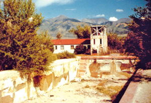 The remains of the old pool are shown with the former bathhouse in the background in this photo taken in 1984, several years before restoration work began on the facility.  Courtesy of Victor Summers.